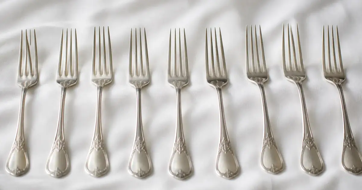 Silver forks in a row on a white cloth